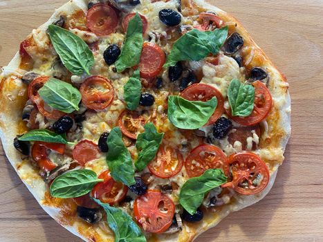 Delicious freshly baked pizza, just out of the oven on a wooden board.