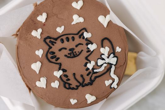 Close up of bento cake with cute picture of cat and white sugar hearts in eco box-packaging with wooden spoon.