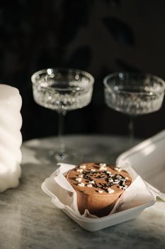 Chocolate bento cake with white candle and chmpagne glasses on luzury marble table.