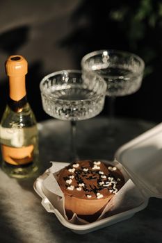 Chocolate bento cake with little champagne for a little birthday party. Exquisite champagne glasses on luzury marble table. Cake for two person. Birthday concept.