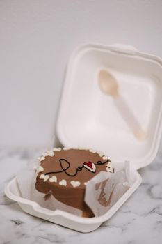 Bento cake with inscription love and white sugar hearts in plastic box-packaging.