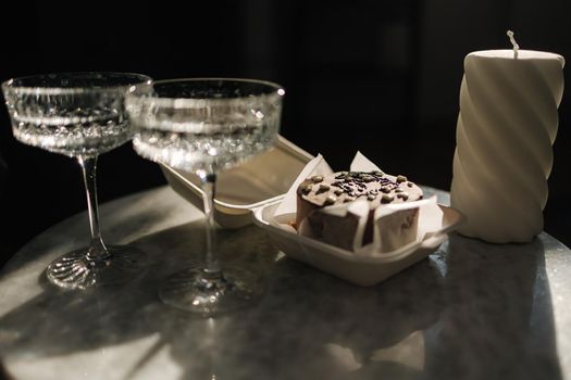 Chocolate bento cake with little champagne for a little birthday party. Exquisite champagne glasses on luzury marble table. Cake for two person. Birthday concept.