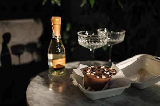 Chocolate bento cake with little champagne for a little birthday party. Exquisite champagne glasses on luzury marble table. Cake for two person. Birthday concept.