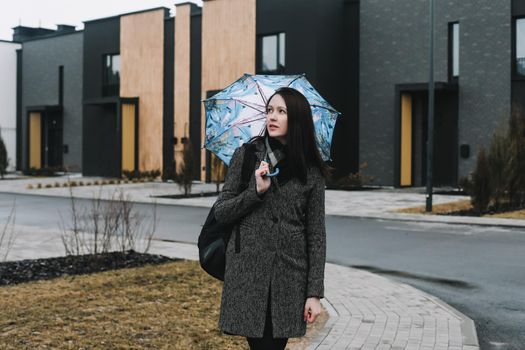 Portrait of a young woman with umbrella outdoors in the street.