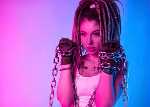 a fighter girl with chains on her hands with beautiful dreadlocks on her head in the neon light