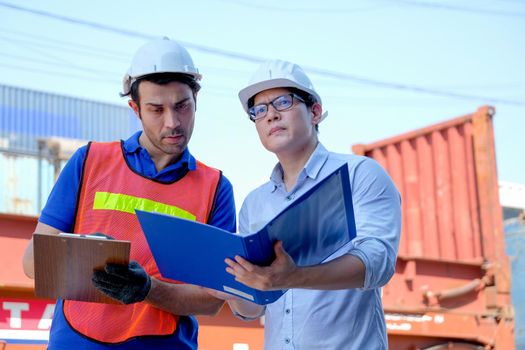 Technician and engineer work together for checking quality and product in cargo container shipping area.
