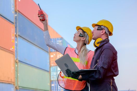 Worker woman use walkie-talkie point to some directions and discuss with technician man who is holding the laptop.