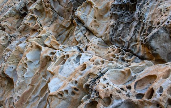 Texture, background layers and cracks in sedimentary rock on cliff face. Cliff of rock mountain. Rock slate in the mountain. Seamless abstract background. Cracks and layers of sandstone.