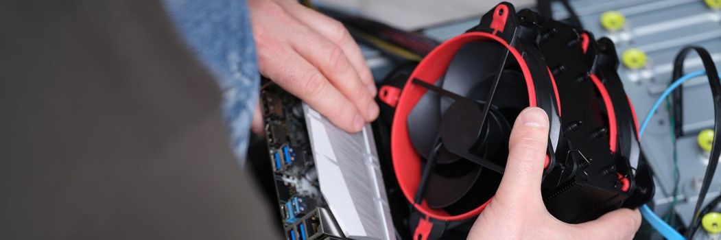 Master repairer holding cooler in front of system unit closeup. Assembly and repair of computer equipment and electronics concept