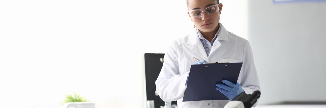 Woman scientist chemist writing in documents in chemical laboratory. Quality control of petroleum products concept