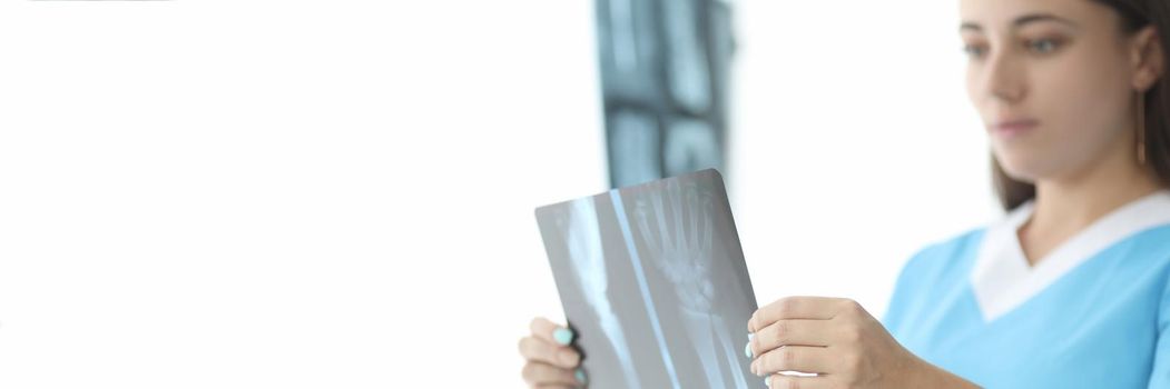 Traumatologist doctor looking at xray of hand in clinic closeup. Diagnosis and treatment of rheumatoid arthritis concept