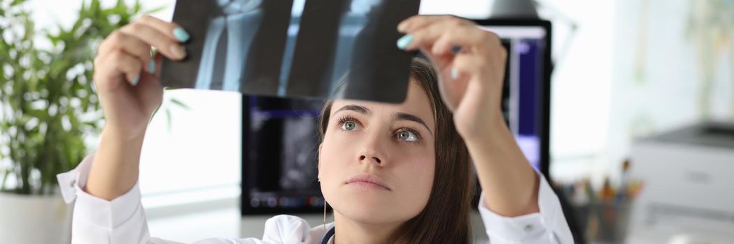 Woman doctor looking at xray of hand in clinic office. Diagnosis and treatment of arthritis concept