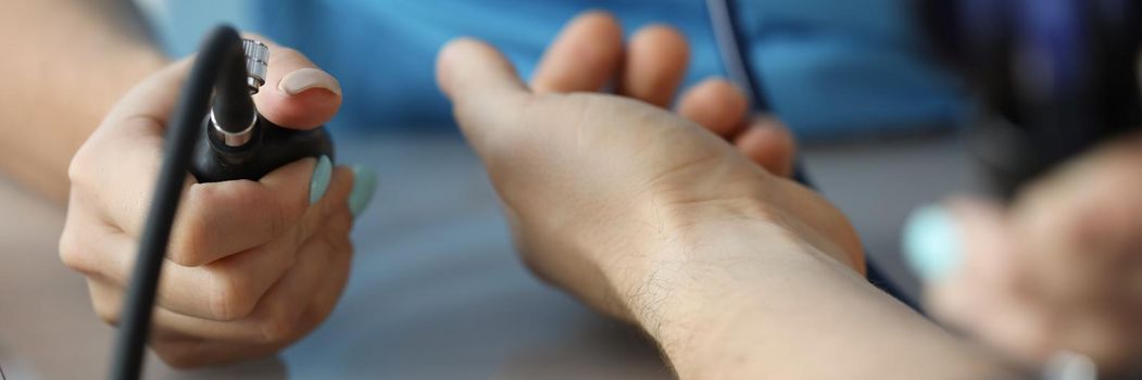 Cardiologist measuring blood pressure to patient in clinic closeup. Principles of arterial hypertension treatment concept