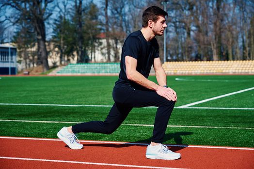 Man in sport clothers does a warm-up exercises at stadium track before jogging outdoors, Healthy lifestyle