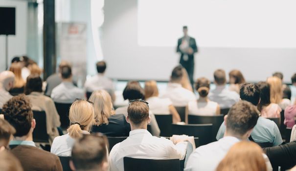 Speaker giving a talk in conference hall at business event. Rear view of unrecognizable people in audience at the conference hall. Business and entrepreneurship concept.