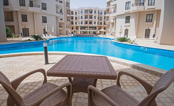 Terrace patio furniture of a luxury apartment in tropical resort with furniture and pool view from balcony