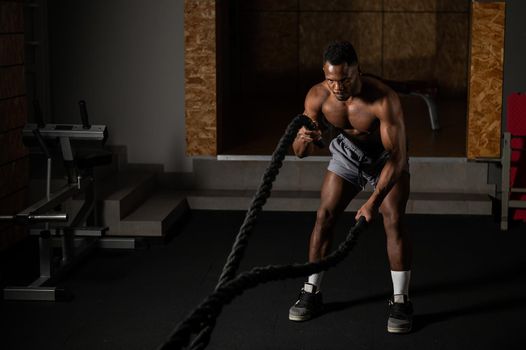 Attractive african american man with naked torso doing endurance exercises with trope