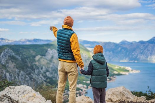 Dad and son travellers enjoys the view of Kotor. Montenegro. Bay of Kotor, Gulf of Kotor, Boka Kotorska and walled old city. Travel with kids to Montenegro concept. Fortifications of Kotor is on UNESCO World Heritage List since 1979.