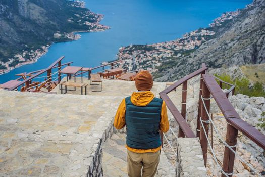 Man tourist enjoys the view of Kotor. Montenegro. Bay of Kotor, Gulf of Kotor, Boka Kotorska and walled old city. Travel to Montenegro concept. Fortifications of Kotor is on UNESCO World Heritage List since 1979.