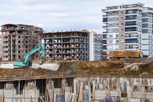 Construction site. Excavator with bucket on construction site against background of houses under construction