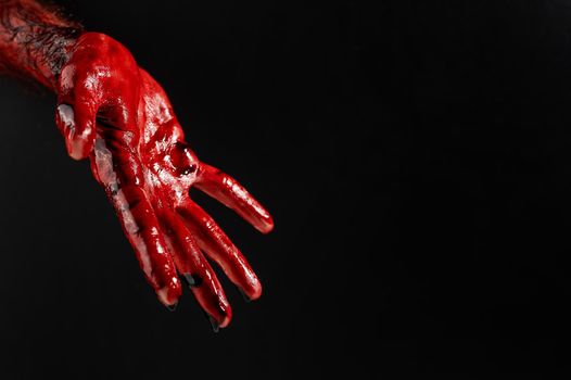 Close-up of a male hand stained with blood on a black background