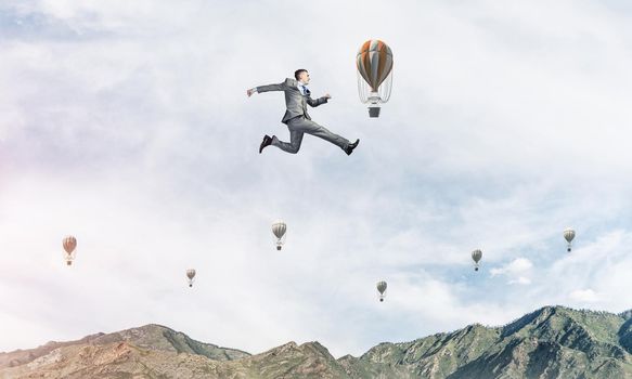 Businessman in suit running in the air as symbol of active life position. Skyscape with flying balloons and nature view on background. 3D rendering.