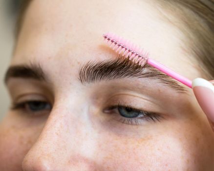 Close-up portrait caucasian woman combing her eyebrows