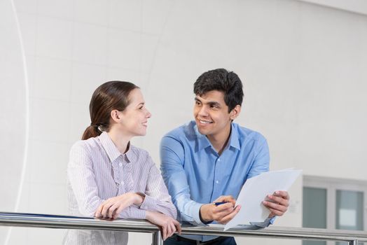businessman and woman discussing document standing on balcony