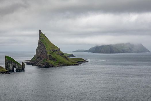 Cloudy wide view of Drangarnir gate, Tindholmur and Mykines island