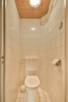 The interior of a toilet decorated with white tiles and a wooden ceiling in a modern house