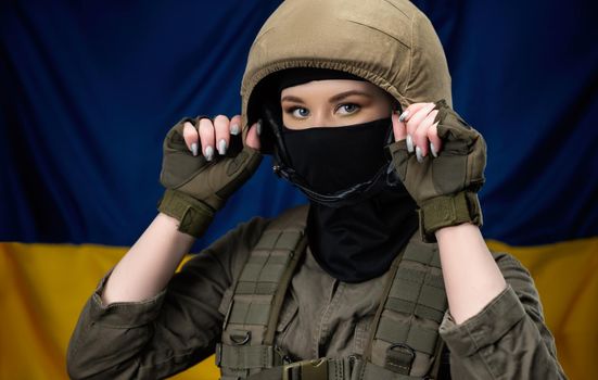 a girl Ukrainian soldier on the background of the flag of Ukraine, wearing a helmet and a bulletproof vest