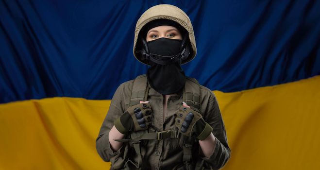 a girl Ukrainian soldier on the background of the flag of Ukraine, wearing a helmet and a bulletproof vest