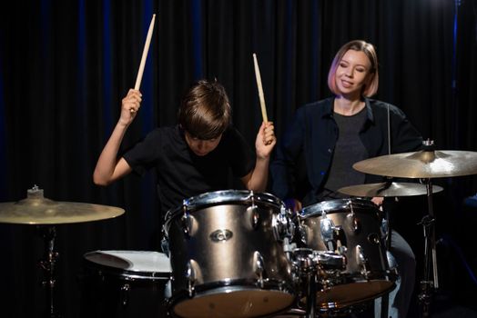 Young woman teaching boy to play drums