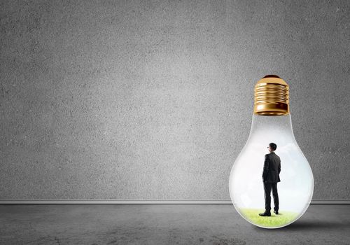 Businessman inside of light bulb in empty concrete room