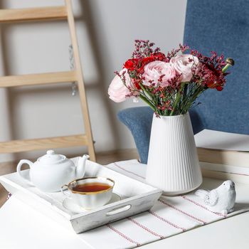 Bouquet of red and pink Persian buttercups on a white table. Scandinavian style. Place for text