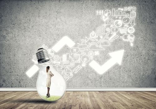 Businesswoman inside of light bulb in empty concrete room