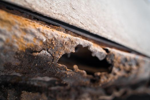 Rusted white car sills close-up. The effect of reagents in winter on an unprotected car body