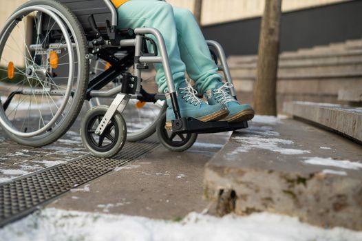 Woman in a wheelchair near the stairs in the park in winter