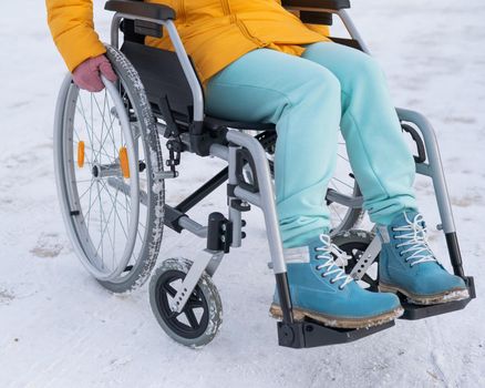 Close-up of hands of a disabled woman in a wheelchair outdoors in winter