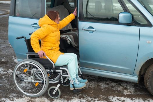 Caucasian woman in a wheelchair gets into the car