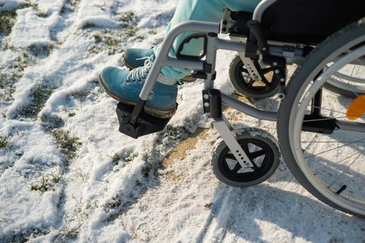 Close-up of legs of woman in wheelchair in winter outdoors