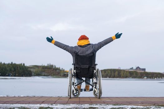 Caucasian woman in a wheelchair walks by the lake in winter