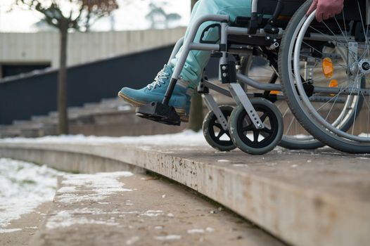 Woman in a wheelchair near the stairs in the park in winter