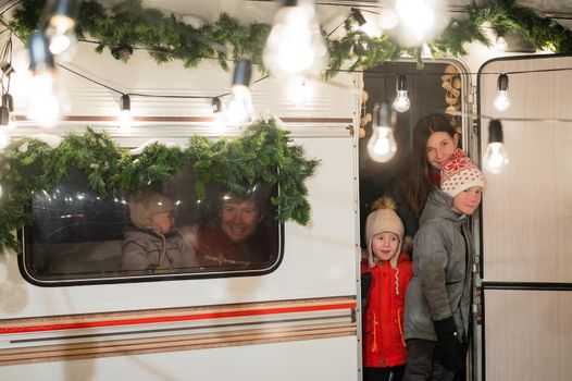 Happy large family celebrates christmas in nature. Parents with three sons travels in a mobile home