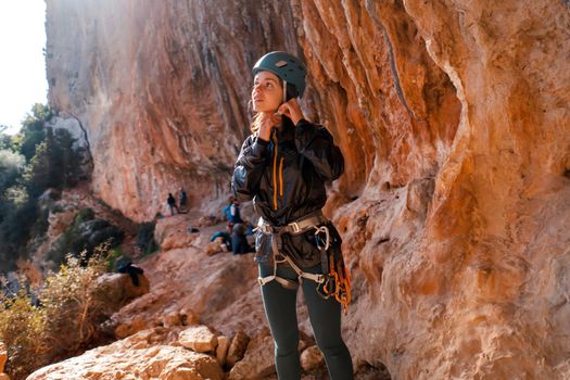 Young girl is preparing for training on the rocks, in the mountains and puts a helmet on her head for safety to protect her health, woman engaged in active sports, in mountaineering and rock climbing.