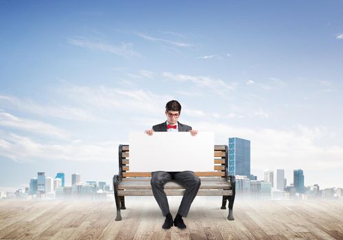 Young businessman holds a large white banner. sits on the bench