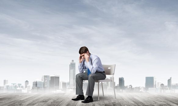 Businessman is sitting on an office chair with his head in his hands. Business stress and problems