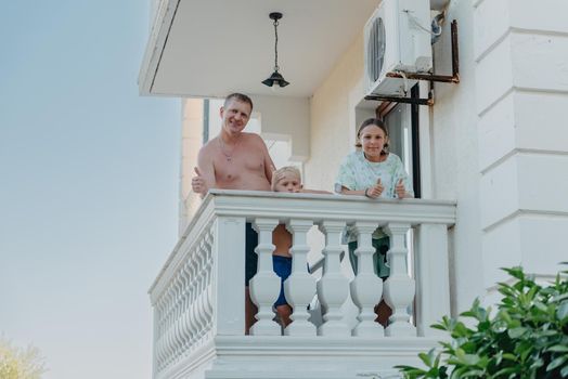 Family of three people on hotel balcony in summer enjoying their vacation.