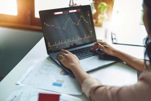 Financial and investment planning concept, female businesswoman using computer to analyze charts to find entry points on a trading board. through digital media via the internet