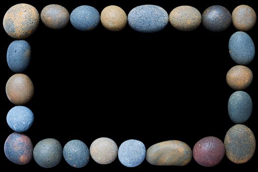 A frame of coloured pebbles on a black copy space background